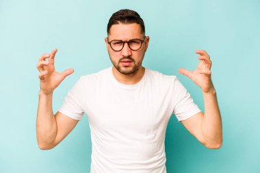 Genç İspanyol adam mavi arka planda izole edilmiş öfkeyle bağırıyor..