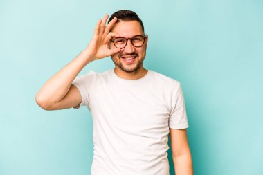 Latin kökenli genç adam mavi arka planda izole edilmiş. Heyecanlı..