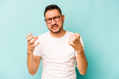 Mavi arka planda izole edilmiş genç İspanyol adam gergin elleriyle çığlık atıyor..