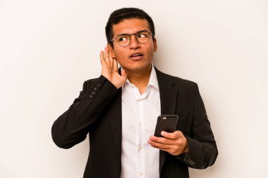 Beyaz arka planda izole edilmiş cep telefonu tutan İspanyol genç bir adam bir dedikoduyu dinlemeye çalışıyor..