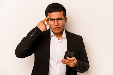 Beyaz arka planda cep telefonu tutan İspanyol genç adam işaret parmağıyla hayal kırıklığı gösteriyor..