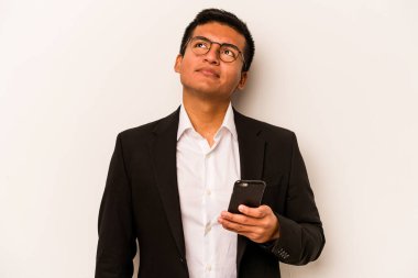 Genç İspanyol iş adamı cep telefonunu beyaz arka planda izole ederek hedeflerine ve amaçlarına ulaşmayı hayal ediyor.