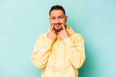 Latin kökenli genç bir adam mavi arka planda iki seçenek arasında kuşkulanıyor..