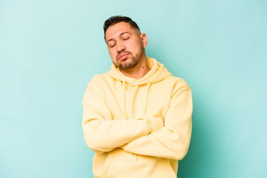 Genç İspanyol adam mavi arka planda izole edilmiş. Tekrarlanan bir görevden yorulmuş..