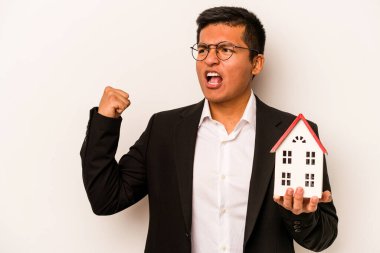 Beyaz arka planda izole edilmiş küçük bir evi tutan İspanyol genç adam zafer kazandıktan sonra yumruğunu kaldırdı, kazanan konsept.