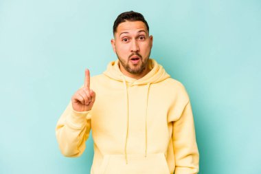 Latin kökenli genç bir adam mavi arka planda izole edilmiş. Harika bir fikri var, yaratıcılık kavramı..