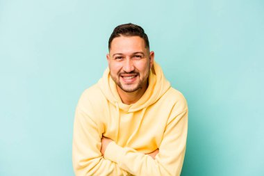 Genç İspanyol adam mavi arka planda izole edilmiş gülüyor ve eğleniyor..