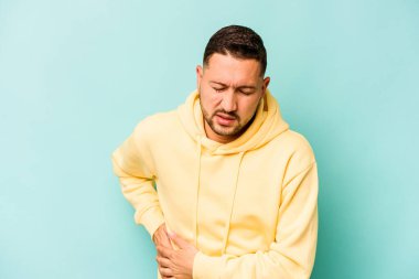 Mavi arka planda karaciğer ağrısı ve karın ağrısı çeken genç bir İspanyol..