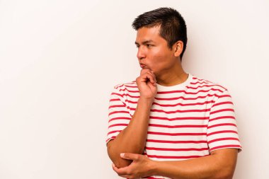 Beyaz arka planda izole edilmiş genç bir İspanyol şüpheli ve şüpheci bir ifadeyle yana bakıyor..