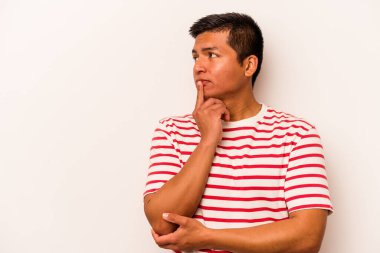 Beyaz arka planda izole edilmiş genç bir İspanyol şüpheli ve şüpheci bir ifadeyle yana bakıyor..