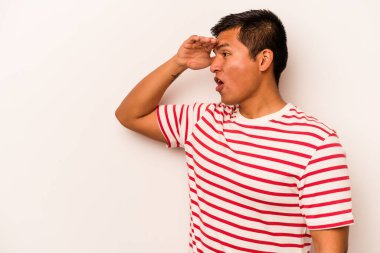 Beyaz arka planda izole edilmiş genç İspanyol adam uzaklara bakıyor ve elini alnına koyuyor..