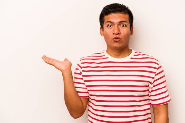 Beyaz arka planda izole edilmiş genç İspanyol adam, avuç içinde kopya alanı tutmaktan etkilenmiş..