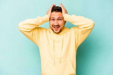 Genç İspanyol adam mavi arka planda izole edilmiş bağırıyor, çok heyecanlı, tutkulu, bir şeyden memnun..