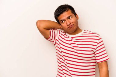 Genç İspanyol bir adam beyaz arka planda izole edilmiş kafasının arkasına dokunuyor, düşünüyor ve bir seçim yapıyor..