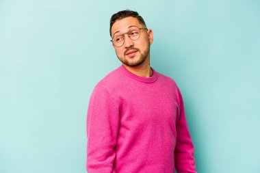 Mavi arka planda soyutlanmış genç bir İspanyol gülümsüyor, neşeli ve keyifli görünüyor..