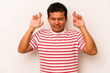 Latin kökenli genç bir adam beyaz arka planda izole edilmiş şans dilemek için şans diliyor.