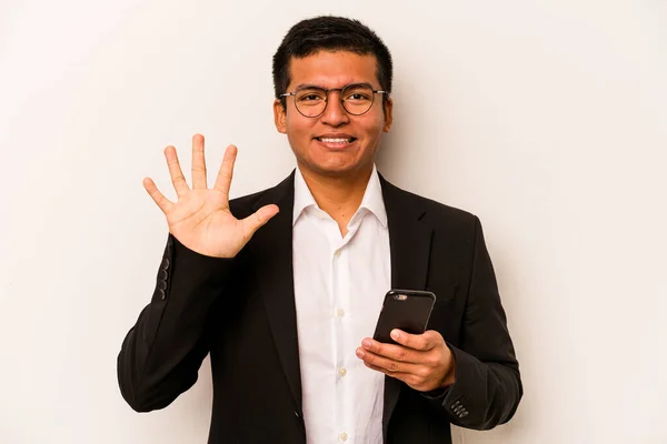 若いビジネスヒスパニック男保持携帯電話隔離された上に白い背景笑顔陽気に示す番号5とともに指 — ストック写真
