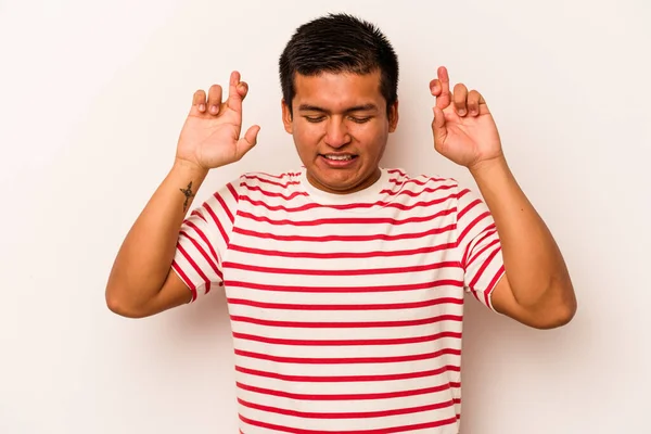 Latin kökenli genç bir adam beyaz arka planda izole edilmiş şans dilemek için şans diliyor.