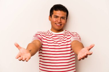 Beyaz arka planda izole edilmiş genç bir İspanyol hoş geldin ifadesi sergiliyor..