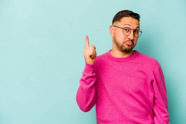 Mavi arka planda izole edilmiş genç İspanyol bir numara parmağıyla görünüyor..