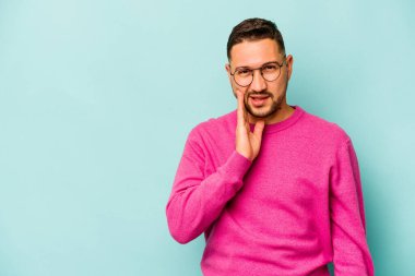 Mavi arka planda izole edilmiş genç bir İspanyol yüksek sesle bağırıyor, gözleri açık ve elleri gergin tutuyor..