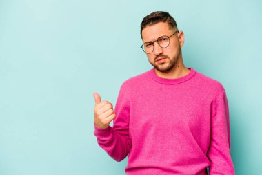 Mavi arka planda izole edilmiş genç İspanyol adam işaret parmağıyla fotokopi alanını işaret ederek şok oldu..
