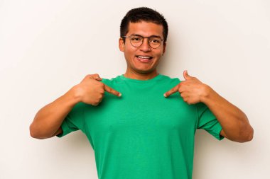 Beyaz arka planda izole edilmiş genç İspanyol adam parmağını göstererek şaşırdı, geniş bir gülümsemeyle..