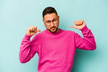 Mavi arka planda izole edilmiş genç bir İspanyol gururlu ve kendinden emin hissediyor, örnek olarak..