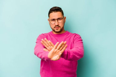 Mavi arka planda izole edilmiş genç İspanyol adam elini uzatmış, dur işareti göstererek seni engelliyor..