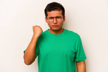 Beyaz arka planda izole edilmiş genç İspanyol adam kameraya yumruk gösteriyor, agresif yüz ifadesi..