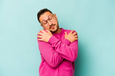 Genç İspanyol adam mavi arka planda yalnızdı. Kucaklaşma, kaygısız gülümseme ve mutluluk..