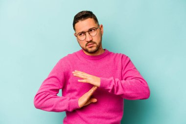 Mavi arka planda izole edilmiş genç İspanyol bir adam bir mola hareketi gösteriyor..