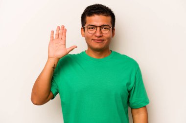 Beyaz arka planda izole edilmiş genç İspanyol adam gülümseyerek beş numarayı parmaklarıyla gösteriyor..