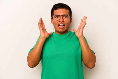 Latin kökenli genç bir adam zaferi ya da başarıyı kutlarken beyaz arka planda mahsur kaldı. Şaşırdı ve şok oldu..