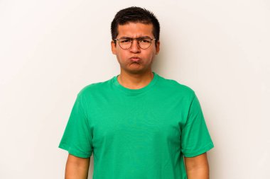 Beyaz arka planda izole edilmiş genç İspanyol adam yanakları patlatıyor, yorgun bir ifadesi var. Yüz ifadesi kavramı.