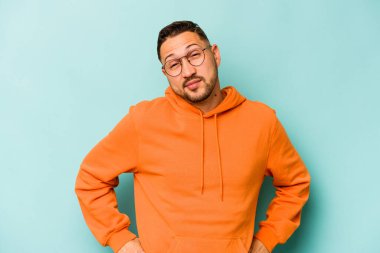 Genç İspanyol adam mavi arka planda izole edilmiş. Amaçlarına ve amaçlarına ulaşmayı hayal ediyor.