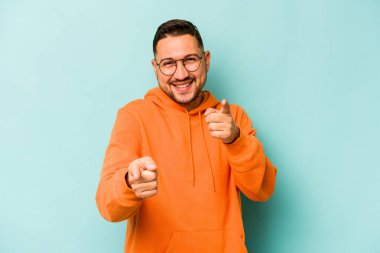 Mavi arka planda izole edilmiş genç İspanyol adam. Önü gösteren neşeli gülücükler..