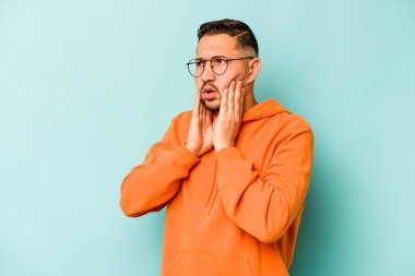 Genç İspanyol adam mavi arka planda izole edilmiş korkmuş ve korkmuş..