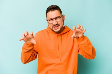 Mavi arka planda izole edilmiş genç İspanyol adam gergin elleriyle çığlık atıyor..