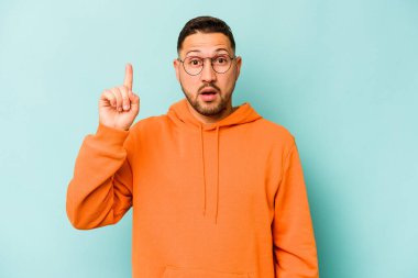 Mavi arka planda izole edilmiş genç bir İspanyol ağzı açık bir şekilde üst tarafı işaret ediyor..