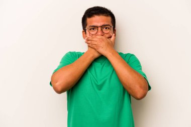 Beyaz arka planda izole edilmiş genç İspanyol adam elleri endişeli bir şekilde ağzı örtüyor..