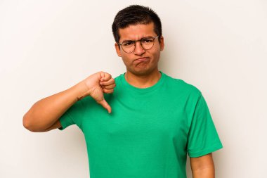 Beyaz arka planda izole edilmiş genç İspanyol adam baş parmağını aşağı gösteriyor, hayal kırıklığı konsepti..