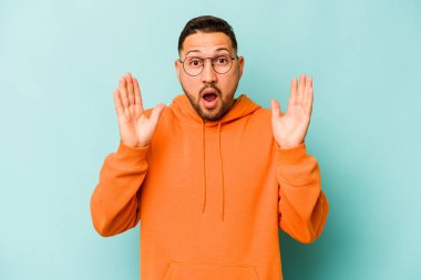 Genç İspanyol adam mavi arka planda izole edildi. Şaşırdı ve şok oldu..