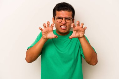 Beyaz arka planda izole edilmiş genç İspanyol bir adam pençelerini bir kediyi taklit ederken gösteriyor, agresif bir hareket..