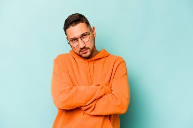 Mavi arka planda izole edilmiş genç bir İspanyol. Sıkılmış, yorgun ve dinlenmeye ihtiyacı var..