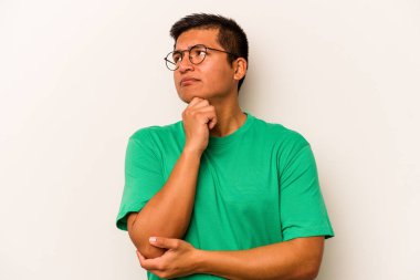 Genç İspanyol bir adam beyaz arka planda izole edilmiş düşünüyor, bakıyor, yansıtıyor, düşünüyor, bir fantezi kuruyor..