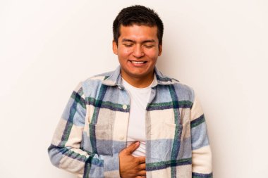 Beyaz arka planda izole edilmiş genç İspanyol adam karnına dokunuyor, nazikçe gülümsüyor, yemek yiyor ve tatmin oluyor..