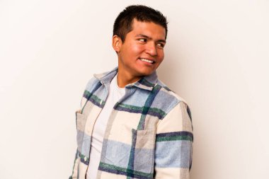 Beyaz arka planda soyutlanmış genç İspanyol adam gülümseyen, neşeli ve keyifli bir kenara bakıyor..