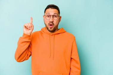 Latin kökenli genç bir adam mavi arka planda izole edilmiş. Harika bir fikri var, yaratıcılık kavramı..