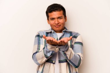 Beyaz arka planda izole edilmiş genç İspanyol bir adam avuçlarıyla bir şey tutuyor ve kameraya sunuyor..